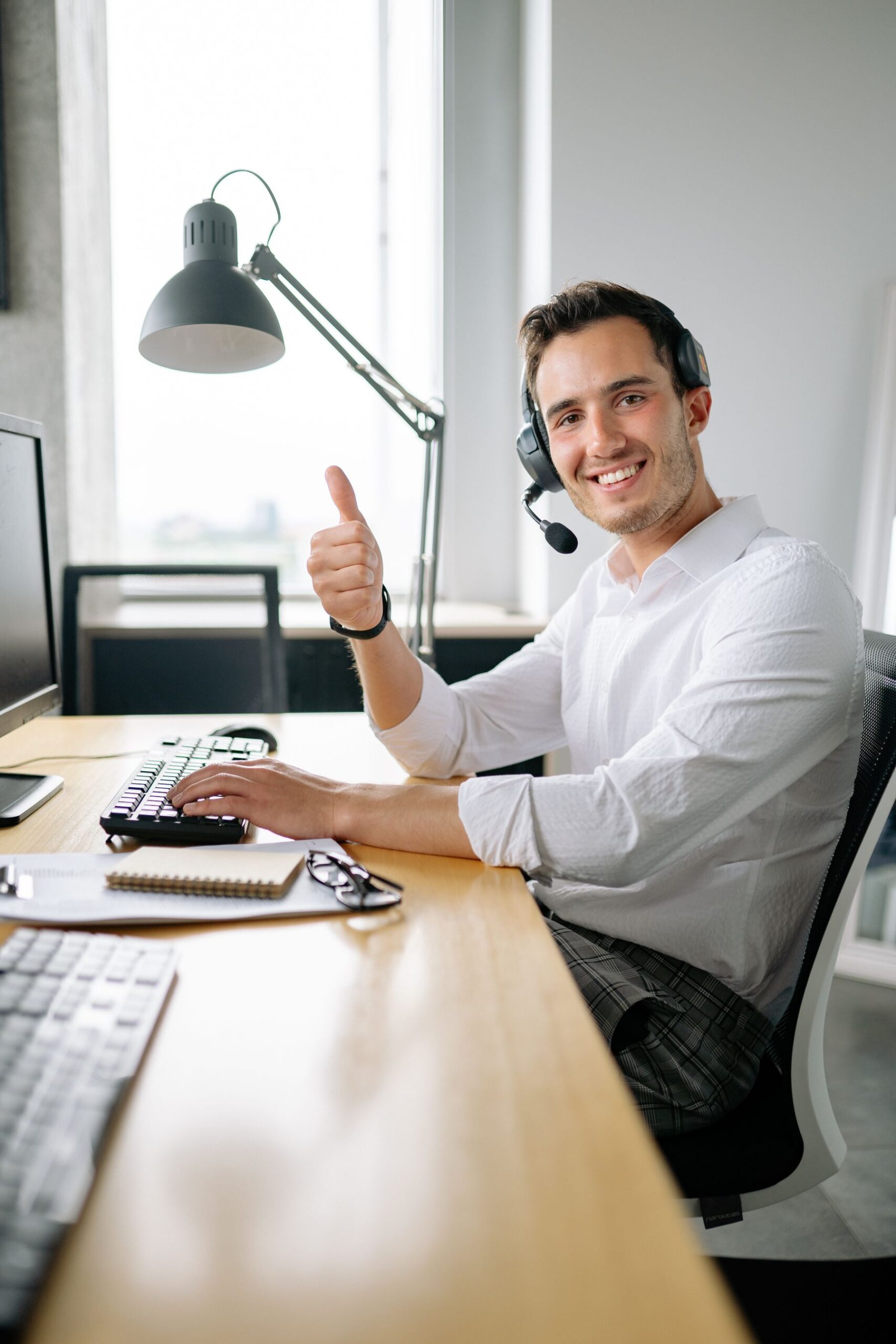 Smiling support agent giving a thumbs up at his desk