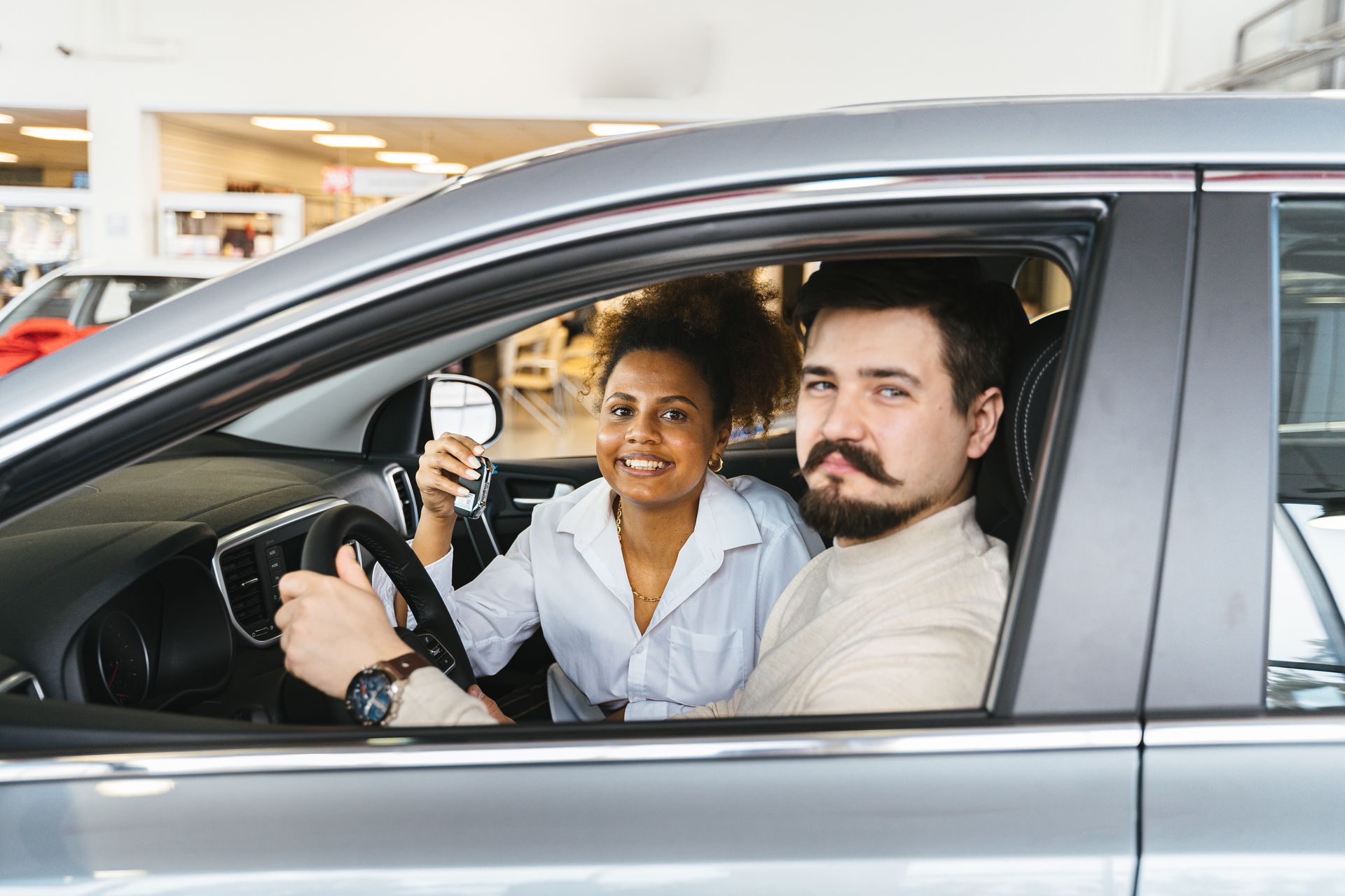 Couple sitting in a new car holding the keys