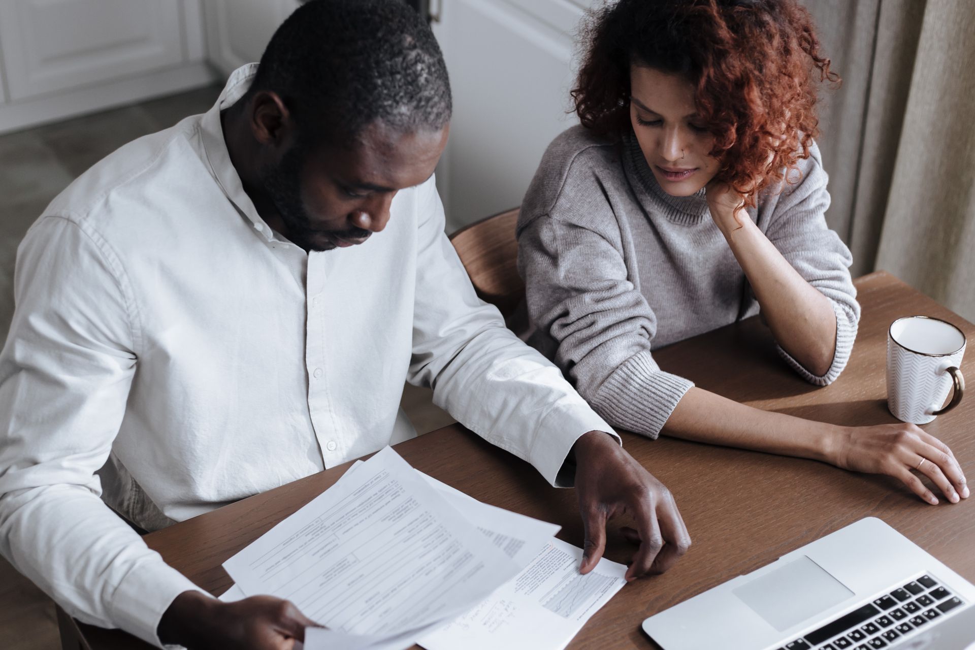 Couple reviewing documents at a desk with a laptop