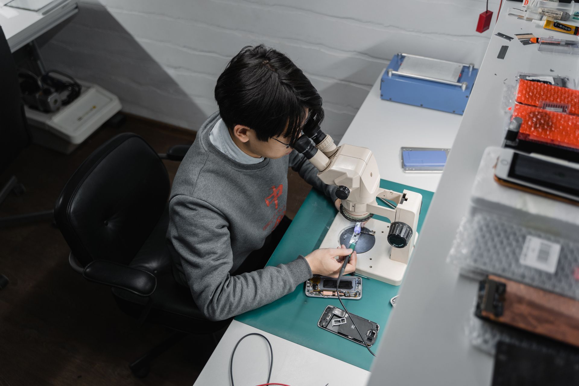 Technician repairing a phone under a microscope